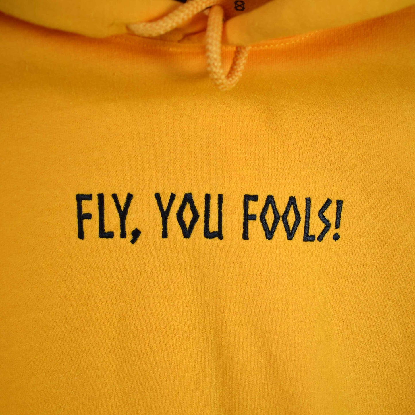 žuta hudica s vezom natpisa "Fly, you fools!"