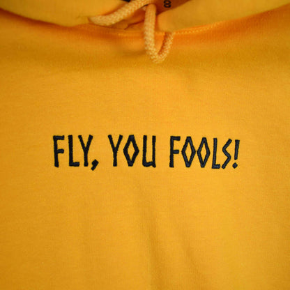 žuta hudica s vezom natpisa "Fly, you fools!"